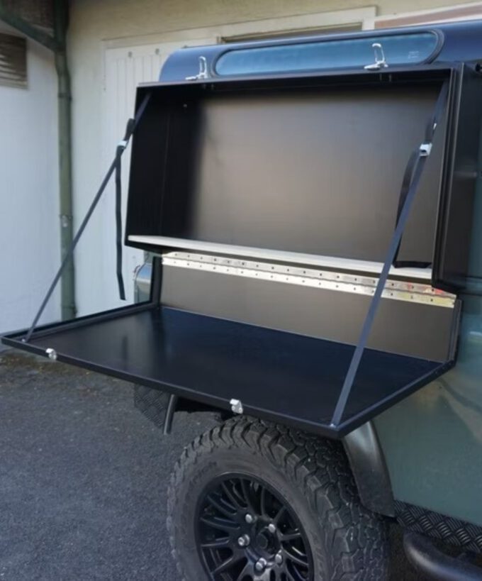 Seitenbox für Defender, Defender Küchenbox, Defender Offroad-Kitchen, Defender Offroad-Küche, Defender Stauraumbox, Defender Werkzeugbox, Defender Klapptisch, aus Aluminium, schwarz matt pulverbeschichtet, am Fahrzeug befestigt, geöffnet, ohne Regalböden